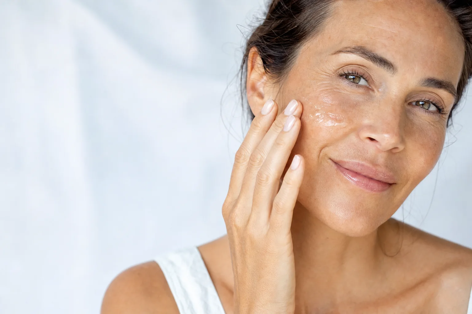 A woman pressing a clear hydrating gel onto her cheek